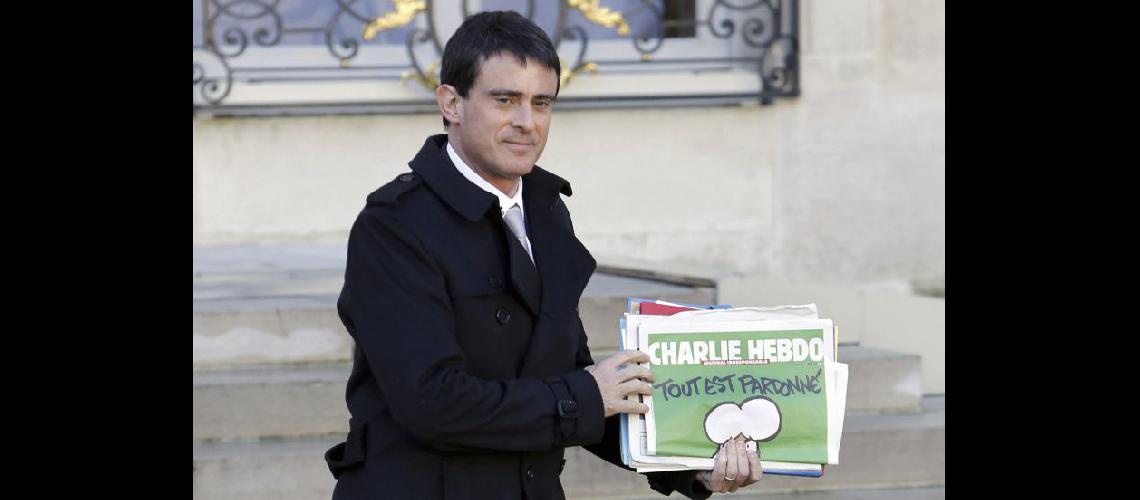  El primer ministro francés Manuel Valls llevando el último número del semanario Charlie Hebdo (NA)