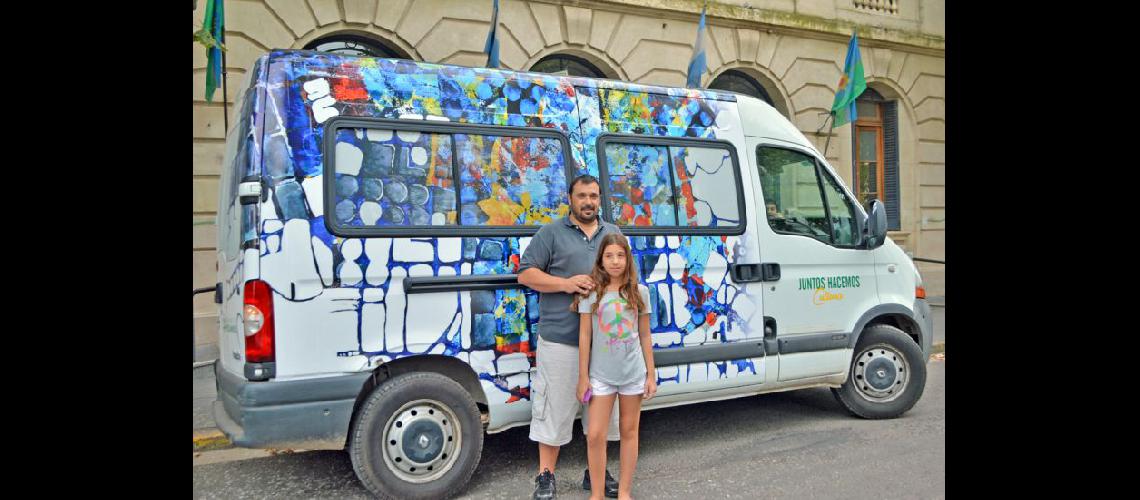  Javier Carrera con su pequeña hija posa junto al vehículo municipal ploteado con su obra (LA OPINION)  