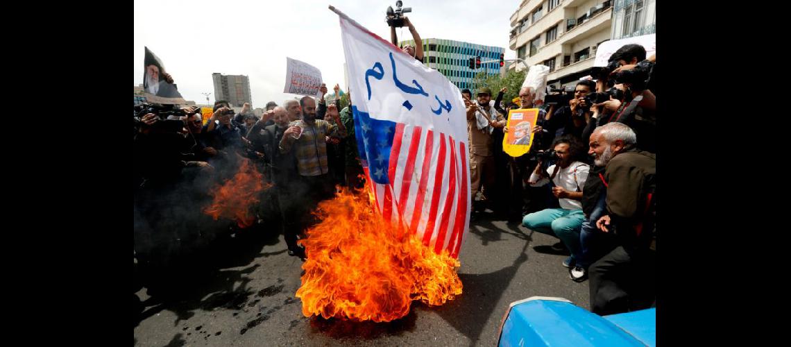  Iraníes queman una bandera estadounidense mientras gritan consignas durante una manifestación en Tehern (NA) 