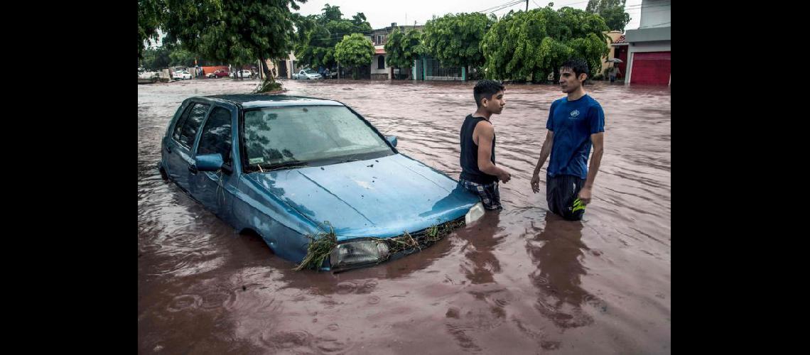  Jóvenes junto a un automóvil ayer en Culiacn Las fuertes lluvias inundaron diferentes vecindarios (NA)