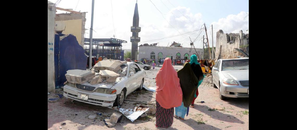  La gente pasa junto a un auto destruido en el lugar de la explosión cerca del parlamento en Mogadiscio (NA)
