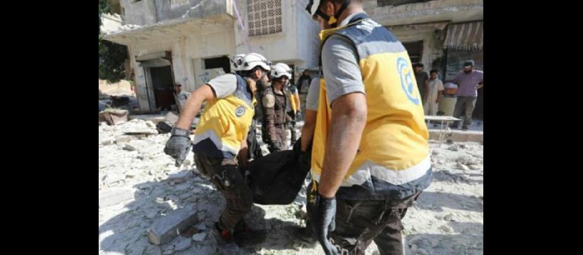  Cascos blancos transportan un cadver entre los escombros causados por bombardeos sobre Kefraya en Siria (AFP)