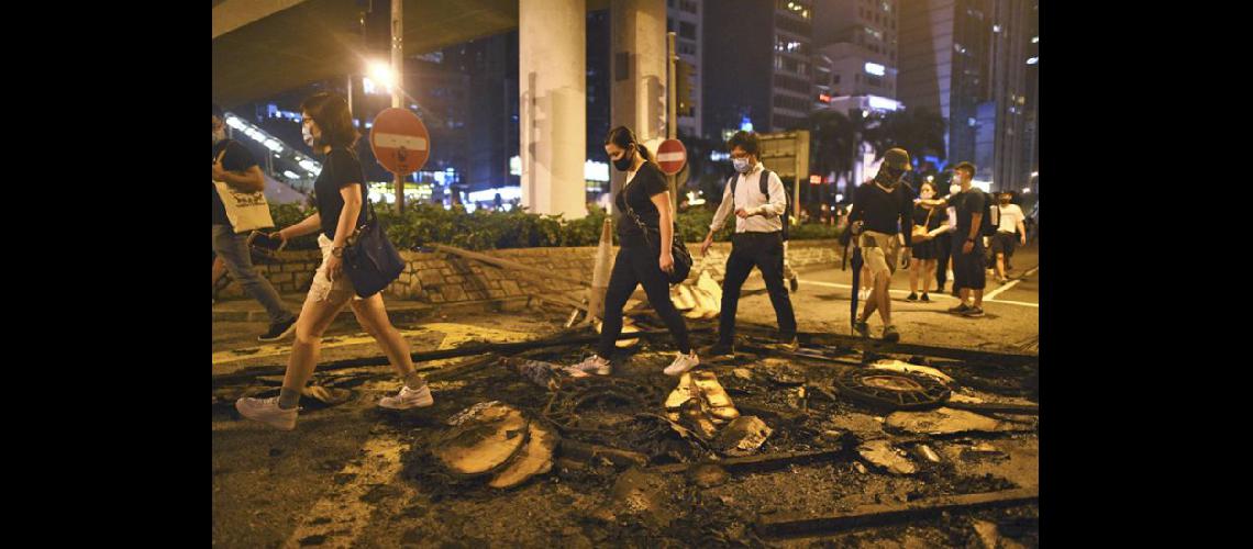  Personas con mscaras pasan sobre escombros quemados en el corazón de Hong Kong tras el anuncio (NA)