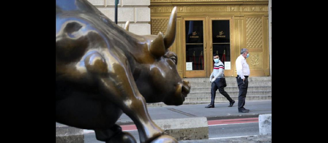 Personas caminan frente al Toro Embistiendo de Wall Street en Nueva York (AGENCIA XINHUA)