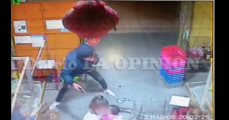 Momentos en el que el delincuente con un arma comete el robo en el súper chino de avenida Illia