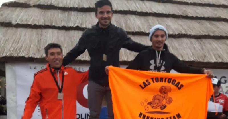 Marcos Misiewicz (a la derecha) en la premiación de su categoría con la bandera de su grupo de amigos Las Tortugas Running Team