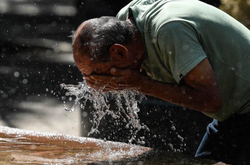 Un hombre se refresca en una fuente durante una ola de calor