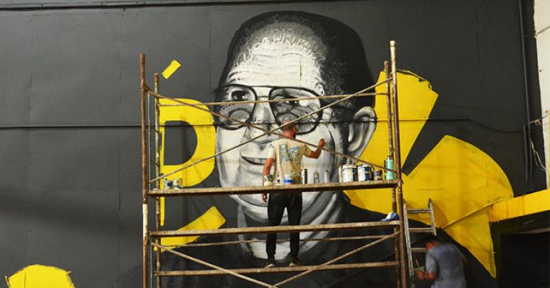 Berna Calabia y su ayudante Juan Surez trabajando en el mural plasmado en una de las paredes del gimnasio del Club Comunicaciones